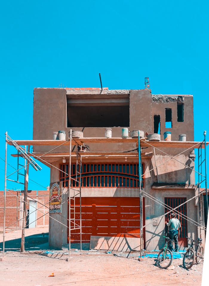 Worker at a construction site in Ferreñafe, Peru with scaffolding under a clear blue sky.